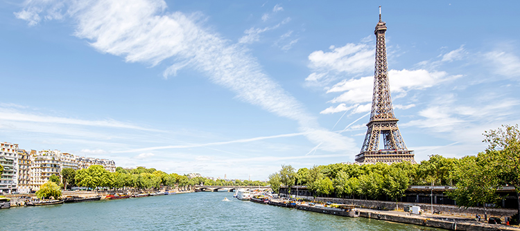 The wide River Seine drifts alongside the Eiffel Tower and other buildings of Paris