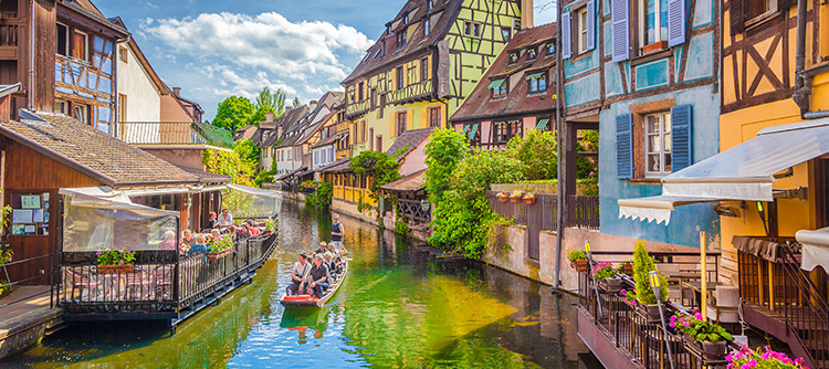 A small boat on a Strasbourg canal, between colorful half-timbered houses