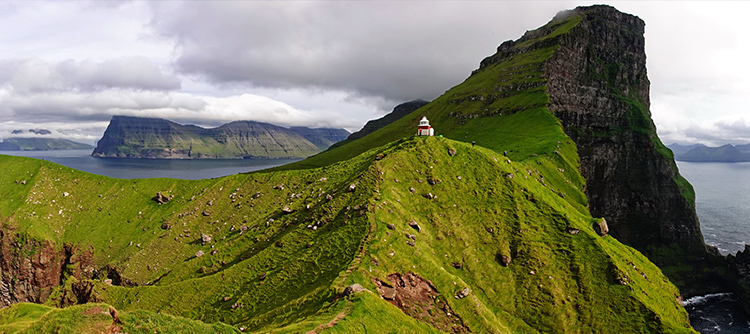 Kallur lighthouse on Kalsoy island on Faroe islands with cliffs, sea, and grass