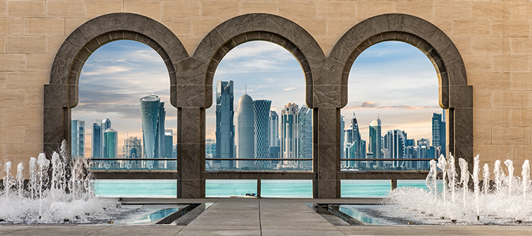 The city of Doha seen through arches, with water fountains in the foreground