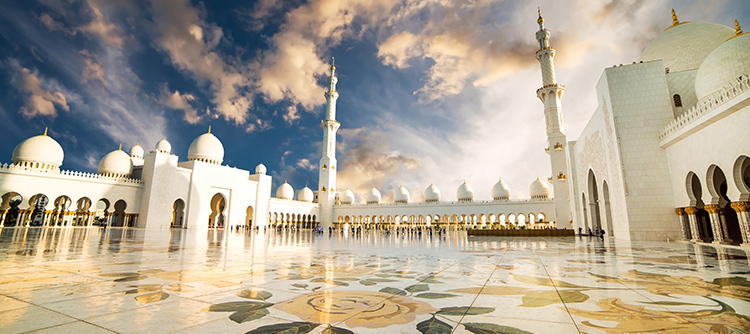 The stunning Grand Mosque in Abu Dhabi, with alabaster domes and minarets and beautiful floral mosaics on the ground.