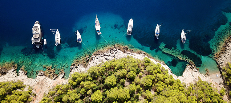 Tropical mediterranean paradise island bay with luxury yachts docked and turquoise clear sea