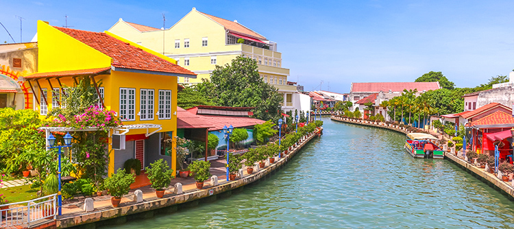 A canal winds between colorful, tropical-looking homes in Malacca.