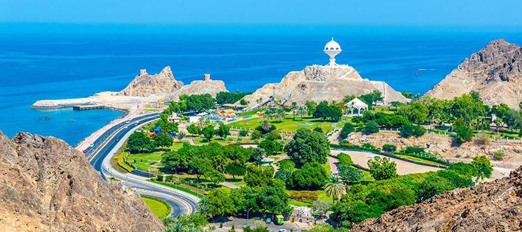Shoreline, greenery and mountains in Muscat, Oman with iconic giant incense burner